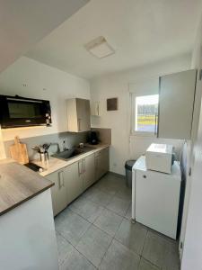 a kitchen with white cabinets and a sink and a refrigerator at La Pause Nature in Incheville +4 photos