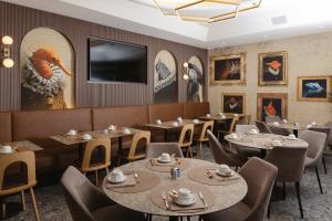 a restaurant with tables and chairs and a flat screen tv at Hotel Marco Polo in Lido di Jesolo
