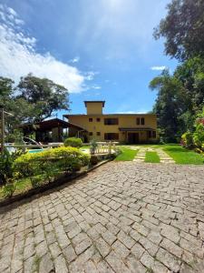 新利马PISCINA AQUECIDA, 5 SUÍTES, trilha privativa até o riacho, Wi-fi, estacionamento, ampla área externa cercada de natureza exuberante - 200m do vilarejo的一栋前面有砖砌车道的房子