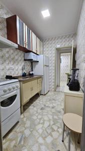 a kitchen with a white refrigerator and a table at Apartamento com piscina à 1km da praia in Caraguatatuba +26 photos