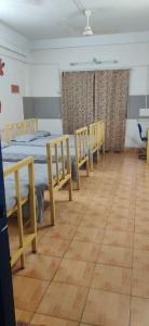 a room with four beds and chairs and a wooden floor at Bedspace Living in Udupi