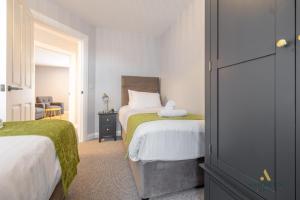 a bedroom with two beds with green sheets and a chair at Ashburn Hotel Apartments 69A in Lurgan