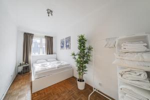 维也纳Perfekte Wohnung für 4 Personen的一间白色卧室,配有床和植物
