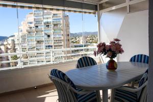 stół z krzesłami i wazon z kwiatami na balkonie w obiekcie Apartamentos Esmeralda Unitursa w mieście Calpe