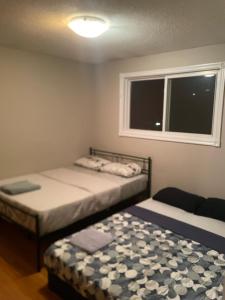 two beds in a small room with a window at Upper Level Cheap Room For 3 People- 24 Hrs Checkin-Walking to Bus,Grocery, Plaza in Kitchener