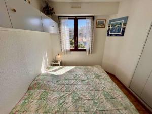 ein Schlafzimmer mit einem Bett in einem Zimmer mit einem Fenster in der Unterkunft Appartement T2 climatisé à Cavalaire, parking privé, proche centre et plages, balcon au calme - FR-1-226B-110 in Cavalaire-sur-Mer