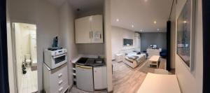 eine kleine Küche und ein Wohnzimmer mit einem Herd in der Unterkunft APPARTEMENT PROCHE CENTRE VILLE, GARE ET AUTOROUTE in Melun