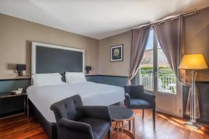 a hotel room with a bed and two chairs and a window at La Villa Mauresque in Saint-Raphaël