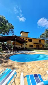 新利马PISCINA AQUECIDA, 5 SUÍTES, trilha privativa até o riacho, Wi-fi, estacionamento, ampla área externa cercada de natureza exuberante - 200m do vilarejo的一座带两把椅子的游泳池以及一座建筑