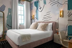 a bedroom with a bed with white sheets and a mural at The Franklin on Rittenhouse, A Boutique Hotel in Philadelphia