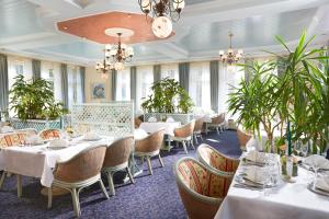 a restaurant with tables and chairs and plants at Landhaus Wacker in Wenden