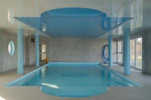 a swimming pool in a building with a blue ceiling at Warsaw Concierge Lake Pool Gym in Zegrze Południowe