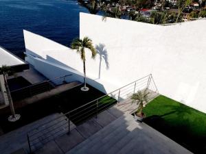 a white building with stairs and palm trees next to the water at Quinta Jalisco Vacation in Tequesquitengo