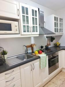 a kitchen with white cabinets and a sink at Cozy beach apartment in Calafell +12 photos