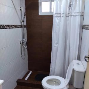 a bathroom with a toilet with a shower curtain at Complejo villa arenas calidas in Necochea