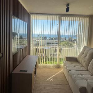 a living room with a couch and a large window at Departamento Av Los Pescadores in Coquimbo