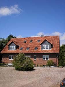 a house with a red roof with windows on it at Ländliche Ferienwohnung In Beliebtem Gästehaus in Windeby