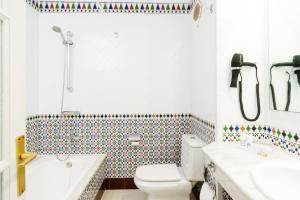 a bathroom with a toilet and a tub and a sink at Plus Fariones Apartamentos in Puerto del Carmen