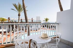 a white table and chairs on a balcony with palm trees at Plus Fariones Apartamentos in Puerto del Carmen