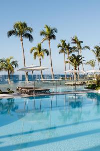 a swimming pool with palm trees and umbrellas at Plus Fariones Suite Hotel in Puerto del Carmen