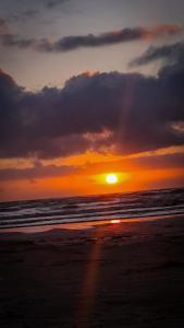 a sunset on a beach with the ocean at Apartamento com piscina à 1km da praia in Caraguatatuba