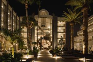 a building with palm trees in front of it at night at Plus Fariones Suite Hotel in Puerto del Carmen