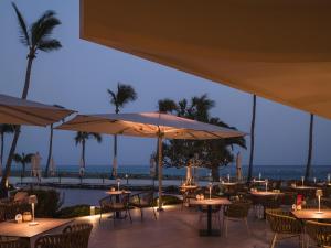 a restaurant with tables and umbrellas overlooking the ocean at Plus Fariones Suite Hotel in Puerto del Carmen
