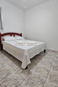 a bedroom with a bed with white sheets and pillows at Apartamento com piscina à 1km da praia in Caraguatatuba