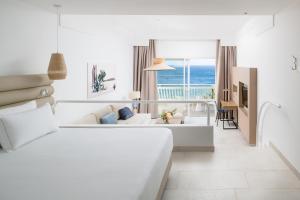 a white living room with a couch and a table at Plus Fariones Suite Hotel in Puerto del Carmen