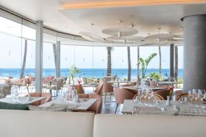 a restaurant with tables and chairs with the ocean in the background at Plus Fariones Suite Hotel in Puerto del Carmen