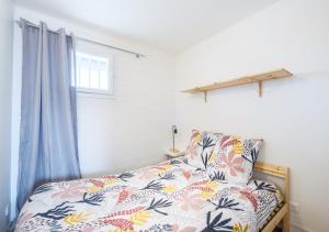 a bedroom with a bed with a floral bedspread and a window at Vagues & Bord de Plage in Biscarrosse