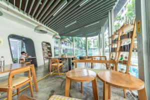 a restaurant with wooden tables and chairs and windows at Elio Sukhumvit 64 in Bangkok