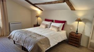 a bedroom with a large bed with red pillows at chambre saint emilion - Le Clos d'Antan in Les Artigues-de-Lussac