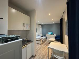 a kitchen with a sink and a living room at Joli Studio Confortable Proche Gare, Centre Ville Et Autoroutes in Melun +27 photos