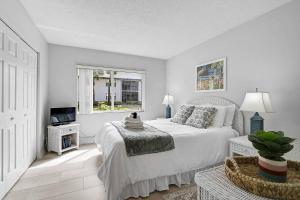 a white bedroom with a bed and a television at Seaside Bliss in Bradenton