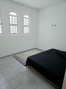 um quarto branco com uma cama e 2 janelas em QUARTO Jd GARCIA em Campinas