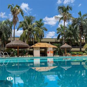 a swimming pool with chairs and umbrellas and palm trees at Hotel OT in Três Lagoas