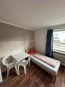 a room with a bed and a table and a window at 2-Rent Group Hostel Apartments HAN53 in Munich