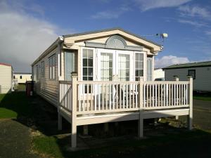 ein kleines Haus mit einem weißen Geländer und einer Veranda in der Unterkunft The Wolds Vogue II 6 Berth Central Heated in Ingoldmells