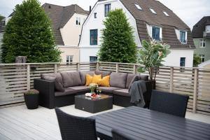 een patio met een bank en tafels op een terras bij Spacious apt, Big roof terrace, Free parking in Stavanger
