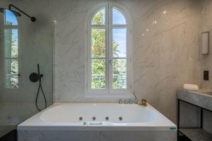 a large white tub in a bathroom with a window at La Villa Mauresque in Saint-Raphaël