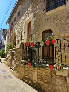 ein Steingebäude mit Topfpflanzen auf einem Balkon in der Unterkunft la petite maison in Céreste