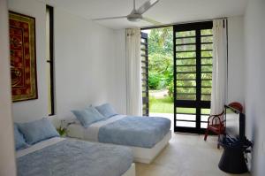 a bedroom with two beds and a sliding glass door at Villa en Club Campestre Mesa de Yeguas in Anapoima