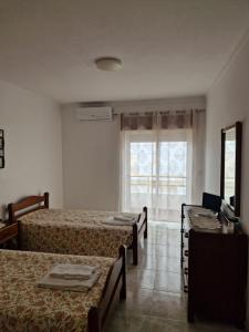 a room with three beds and a window and a television at Algarve Apartment Manta Rota in Vila Nova de Cacela