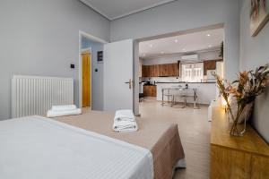 a bedroom with a white bed and a kitchen at Spacious Villa with pool 500m from the beach in Vari