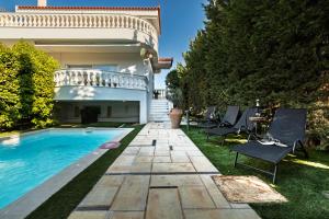 a backyard with a swimming pool and chairs next to a house at Spacious Villa with pool 500m from the beach in Vari