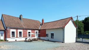 a brick house with a picnic table in the courtyard at Le gîte de Buneville in Buneville