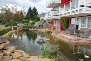 a house with a pond in front of a building at Appartement In Schalkenmehren Mit Schönem Balkon in Schalkenmehren