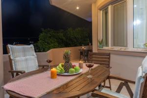a wooden table with a plate of fruit and wine glasses at Casa Anthea 3 bedroom apartment with Garden in Kounoupidhianá +70 photos