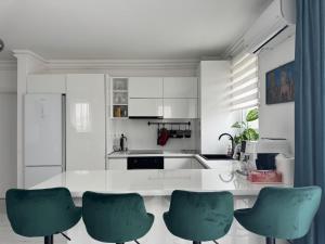 a kitchen with white cabinets and green chairs at 12 Apartament in Târgu-Mureş